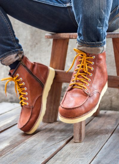 A pair of brown leather boots with laces placed on wooden floor,